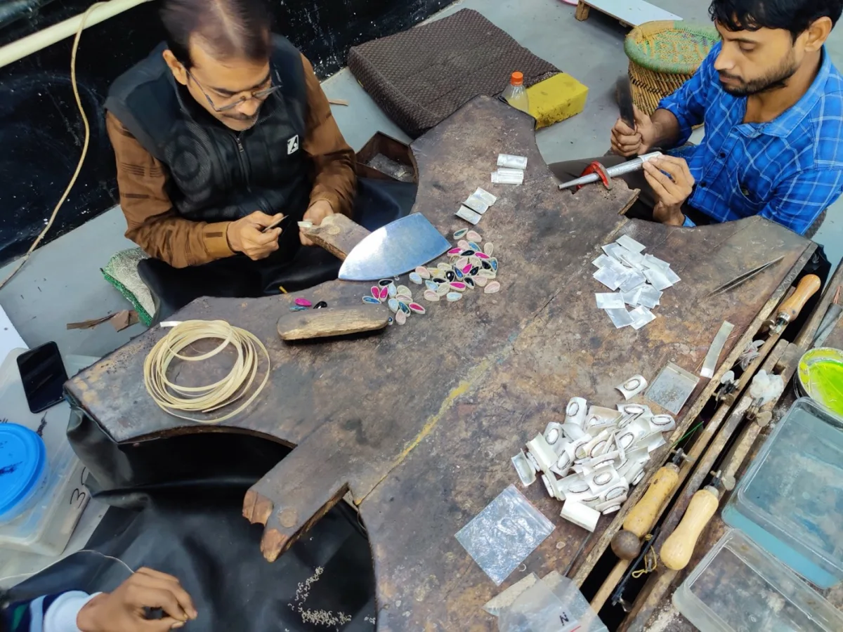 Silver jewelry artisans filing and assembling pieces at a Jaipur workshop bench